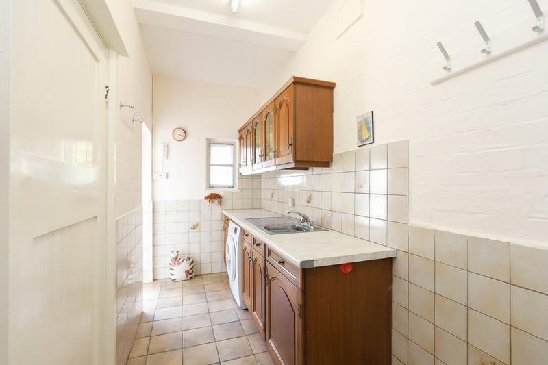A utility room off the kitchen offers a sink and plumbing for a washing machine.