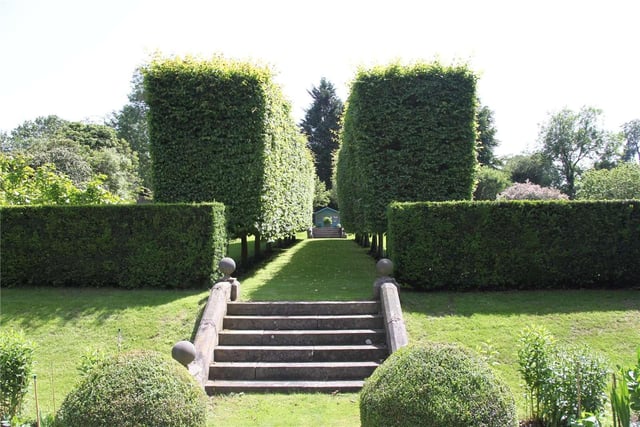 The formal gardens include a paved terrace and lawns with low box hedging, incorporating a playing card design and steps leading up to a walkway between pleached hornbeam
trees and up to a summerhouse.