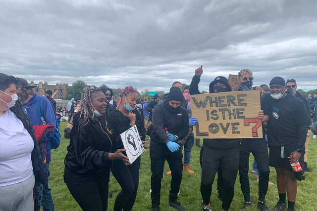 A group of activists stand behind a sign saying 'where is the love' as they spend the afternoon standing up to racism in Holyrood Park