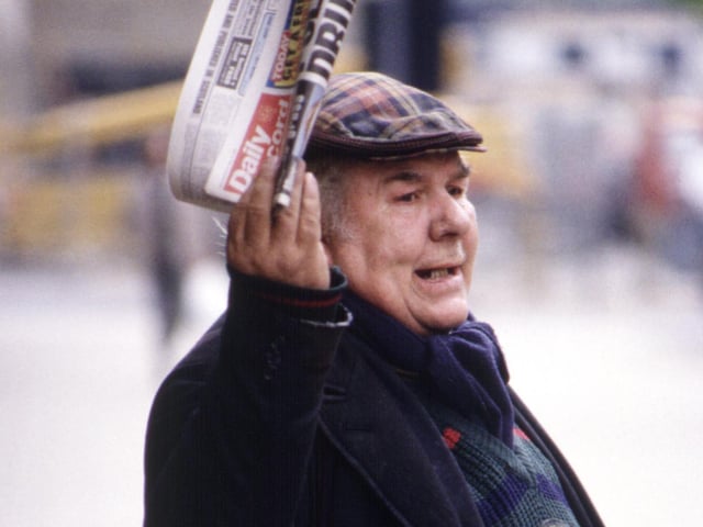 An elderly Glasgow man in a tartan bunnet selling the Daily Record in August 1990.