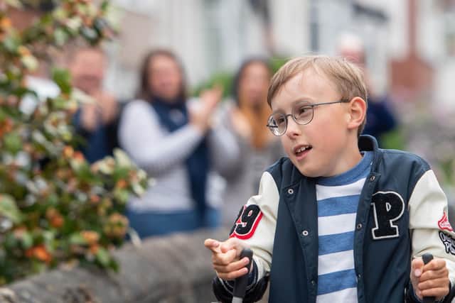 Young fundraiser Tobias Weller, who has cerebral palsy and autism, is cheered on by neighbours as he walks along the street outside his home in Sheffield. Photo: Joe Giddens/PA Wire