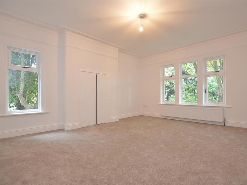 A large 16-foot master bedroom with dual-aspect windows and a fitted storage cupboard within the chimney breast. It has access to an en-suite shower-room.