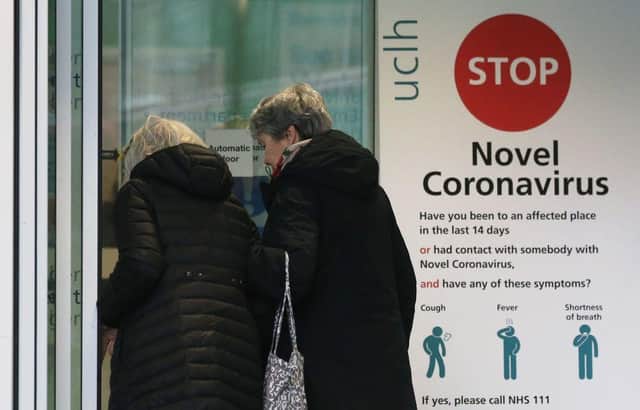 Two women walk past a sign providing guidance information about novel coronavirus (COVID-19) (Photo by ISABEL INFANTES/AFP via Getty Images)