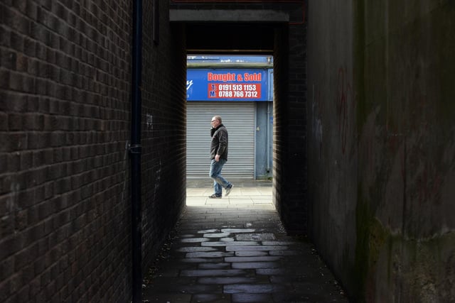 A glimpse of a lone shopper through the alley between Back Railway Street South and Church Street.