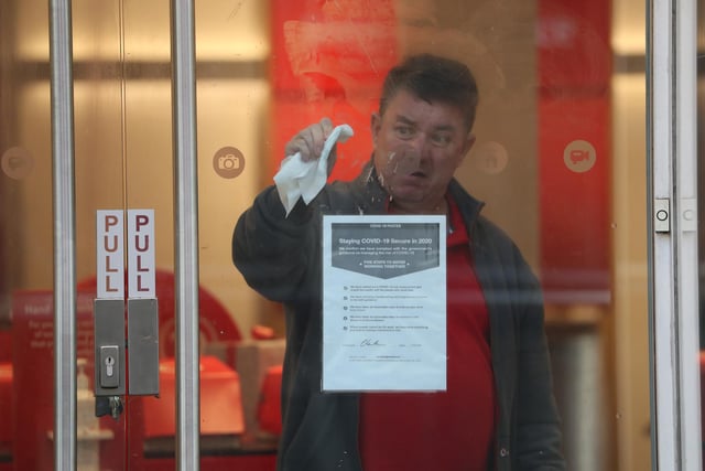 A man cleans the window of a Vodafone store on a quiet Buchanan Street in Glasgow.