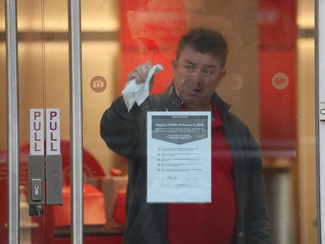 A man cleans the window of a Vodafone store on a quiet Buchanan Street in Glasgow.