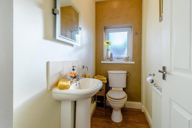 Here is the downstairs toilet, which is at one end of the hallway. It comprises a low-flush WC, pedestal wash hand basin, radiator, laminate floor and opaque double-glazed window.