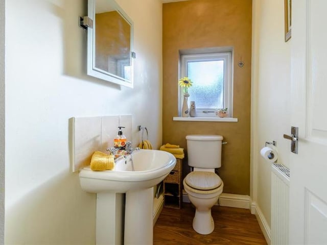 Here is the downstairs toilet, which is at one end of the hallway. It comprises a low-flush WC, pedestal wash hand basin, radiator, laminate floor and opaque double-glazed window.
