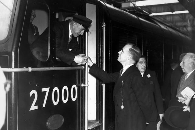 Sir Brian Robertson, chairman of the British Transport commission, greets the driver of the first electric train to leave Sheffield Victoria Station.