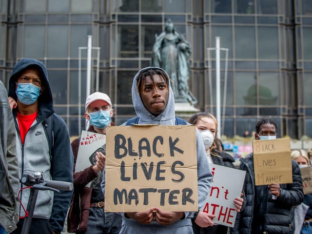 A demonstrator looks up intently as a speaker addresses the crowd on the Guildhall steps.