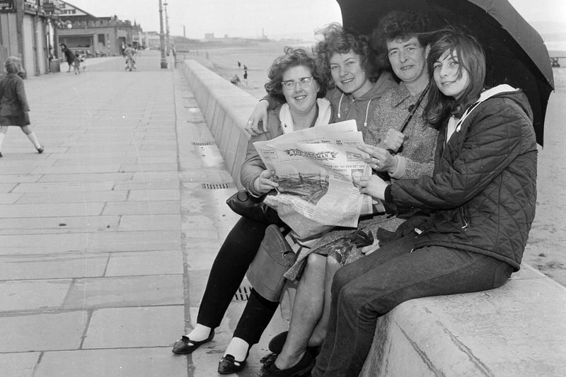 Visitors to Portobello take shelter from the rain in summer 1965 while reading all the day's news in The Scotsman.