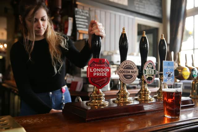 A bartender is pictured as she pulls a pint of Fuller's London Pride beer in a pub (Photo credit should read DANIEL LEAL-OLIVAS/AFP via Getty Images)