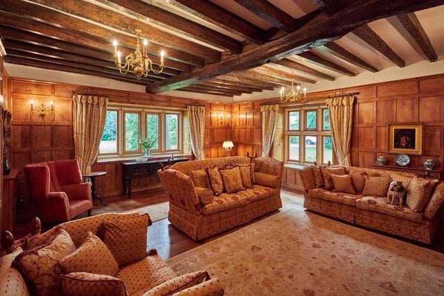 Oak ceiling beams are also still in place in this wonderfully snug room, while  all four walls are adorned in traditional oak panelling, with a decorative fireplace at its heart.