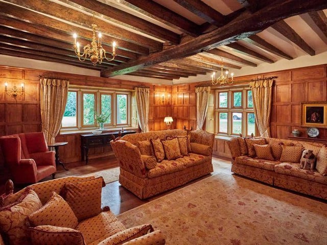 Oak ceiling beams are also still in place in this wonderfully snug room, while  all four walls are adorned in traditional oak panelling, with a decorative fireplace at its heart.