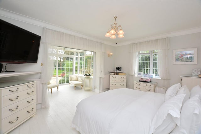 The large master bedroom suite is modern in design, with crisp white furnishings and views overlooking the garden.