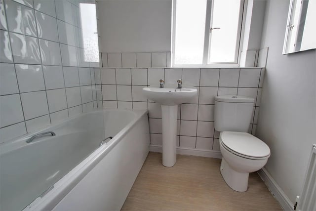 The bathroom is fitted with a modern suite in white. It includes a bath, pedestal wash hand basin and low flush WC. The walls are tiled.