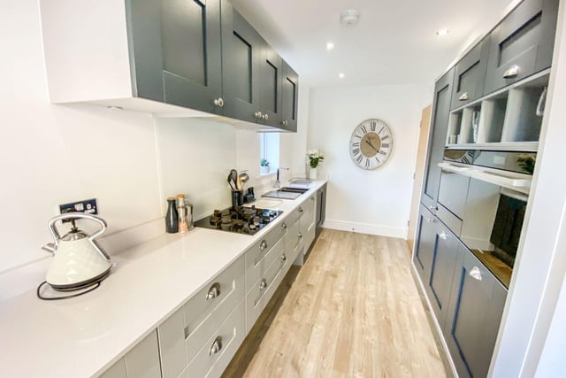 The kitchen diner contains wall and base storage units and various integrated appliances, including a fridge freezer, dishwasher, gas hob oven and microwave.