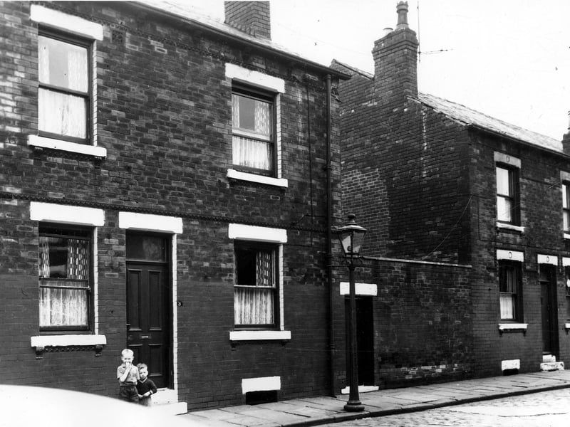 Two back-to-back terraced house separated by a yard, originally built to house the shared outside toilet, in August 1963. On the left two small boys stand outside no 3. This area was soon to be demolished and families relocated as part of a Leeds City Council slum clearance programme.