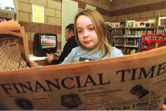 Sarah Mulligan, 8, from Colinton, reads the Financial times while Shaun Currie has a go on the new Playstation at the new Muirhouse Library, which was fully-equipped with internet ready computers with email(!), a Playstation and access to papers, magazines, videos and audio music, 6 January 2000.