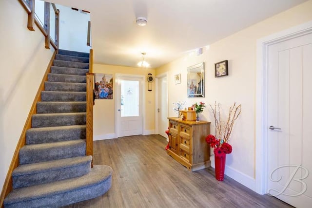 We're heading upstairs now, via this pleasant and welcoming hallway. It features laminate flooring and a wooden staircase with glass balustrade.