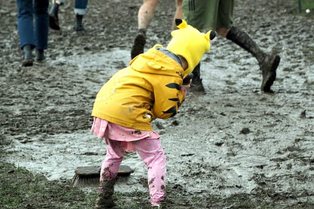 A child helps with mud sweeping near the beer tent by David Bocking