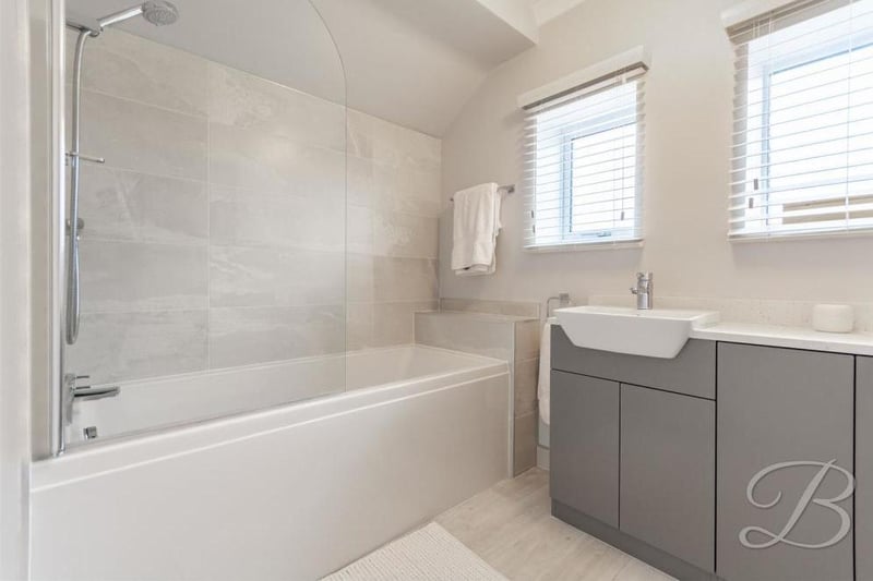 One of the en-suite bathrooms, complete with bath and shower. There is a low-flush WC and central-heating radiator.