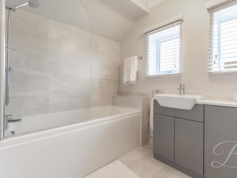 One of the en-suite bathrooms, complete with bath and shower. There is a low-flush WC and central-heating radiator.