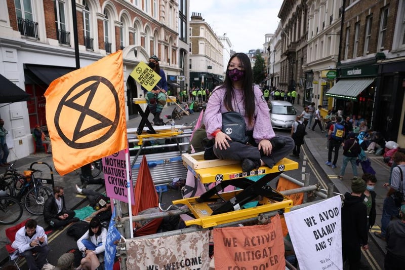 An activist sits atop a makeshift platform erected to help block the road as part of the 'Impossible Rebellion' (Photo by Dan Kitwood/Getty Images)