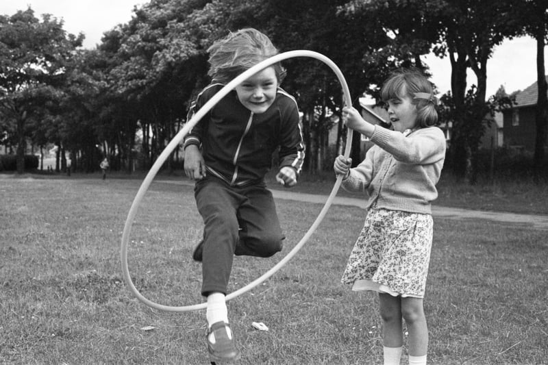 Six-year old Joanne Whiting leaps through the hoop with Lynn Coundon (8) holding on tight at the 1978 playscheme at King George V playing fields.