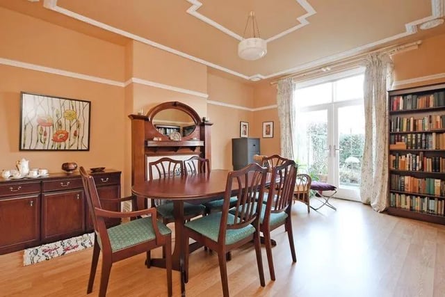 The spacious dining room has a feature fireplace with wooden surround with a mirror inset, cream tiles and an open fireplace. French doors open into the garden to the rear.