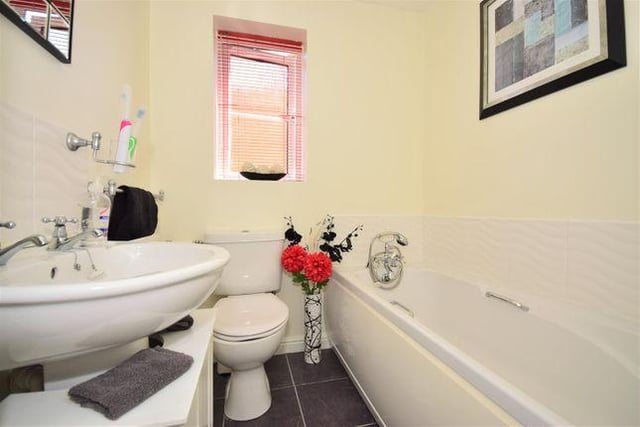 The modern bathroom includes a low-level WC, pedestal washbasin and panel bath with shower attachment, double glazed window, central heating radiator and part tiling around bath and washbasin.