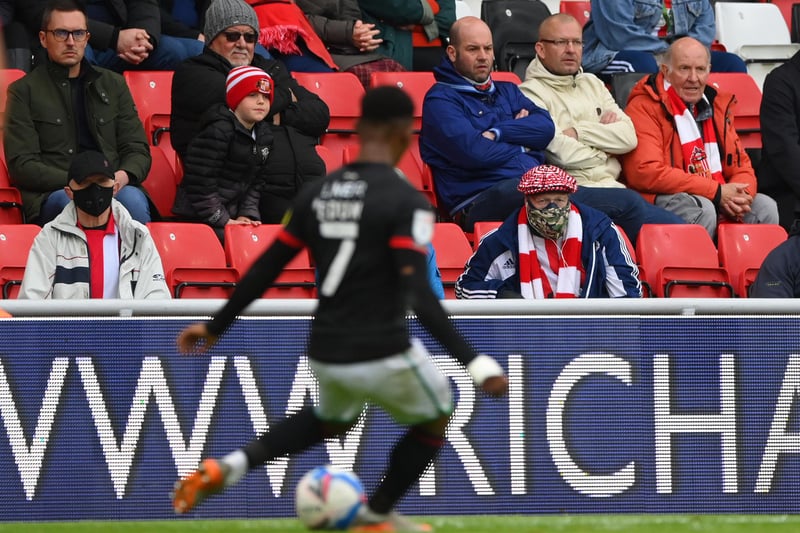 A Sunderland fan wearing a face-covering watches the action from the stand.