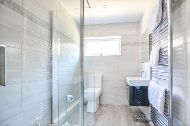 The master en-suite features a walk-in shower. The gentle tones of the tiles and floor create a light feel.