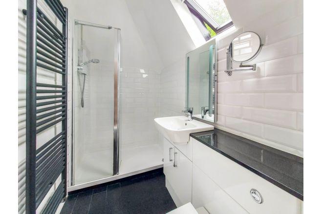 This en-suite bathroom to the master bedroom has a walk-in shower, sink and fitted units.