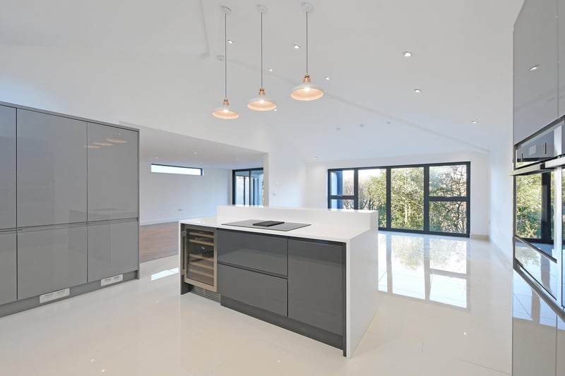 A contemporary dining kitchen with a vaulted ceiling, two Velux roof windows - one with solar powered remote control opening/closingvand tiled flooring with under floor heating. There’s a range of fitted high gloss base/wall and drawer units incorporating an integrated waste disposal unit.