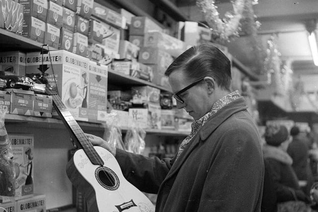 A Christmas shopper inspects a guitar at the Expressions department store in 1962.