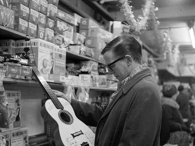 A Christmas shopper inspects a guitar at the Expressions department store in 1962.