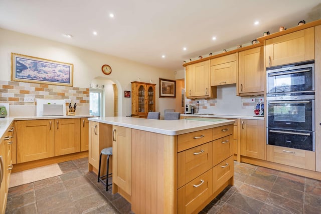 The kitchen/breakfast room which is fitted with modern, wood-fronted cabinet, with curved corner units, topped with granite work surfaces, the kitchen also features an Aga stove set within an arched recess.