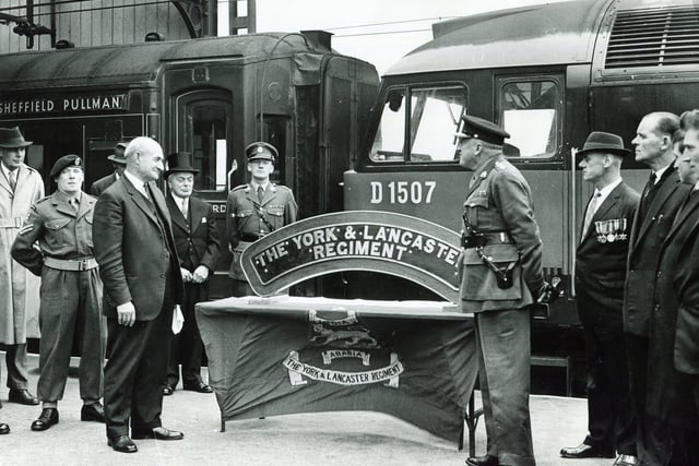 A presentation took place on October 22, 1964, at the Sheffield Victoria Station of a locomotive nameplate to the York & Lancaster Regiment. Our picture shows Mr S C Webb, British Railways Divisional Manager, Sheffield (left), as he presents the nameplate to Brigadier G T Denaro, Colonel of the York & Lancaster Regiment (right).  Also in the picture are members of the regiment and ex-servicemen of the old regiment employed by British Railways, Sheffield. In the background is the Sheffield Pullman express.
