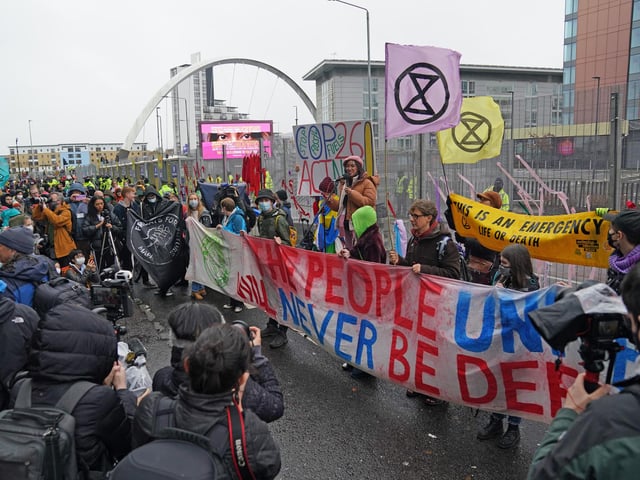 Climate Justice Activists at the Cop26 Gates asking delegates as they make final decisions, "Are You With Us Or With Fossil Fuels?" during the official final day of the Cop26 summit in Glasgow. Picture date: Friday November 12, 2021.