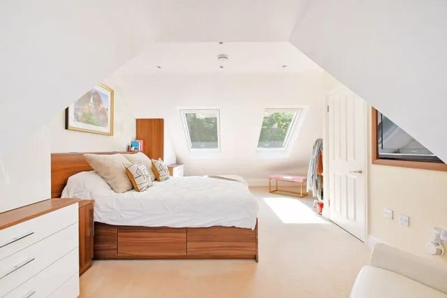 This bedroom is generous in size, with made-to-measure fitted furniture, a recess for a TV within the wall, two larger Velux windows, and rear French doors with a Juliette Balcony and a lovely outlook.