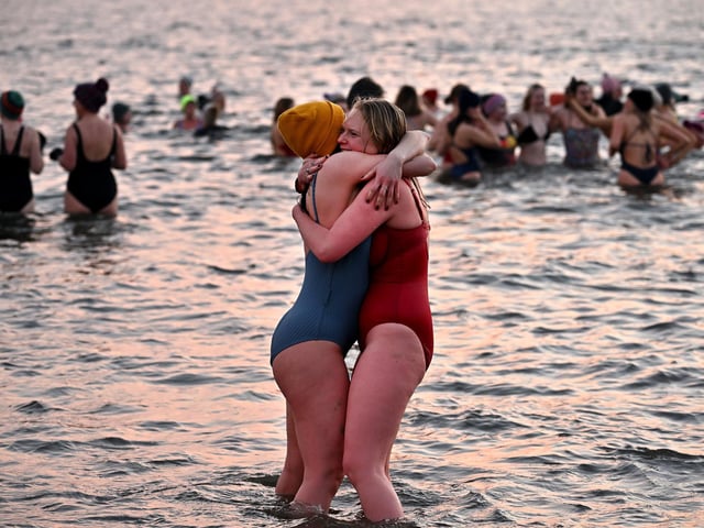 These two women hug to keep warm after braving the cold waters, (Photo by Jeff J Mitchell/Getty Images)