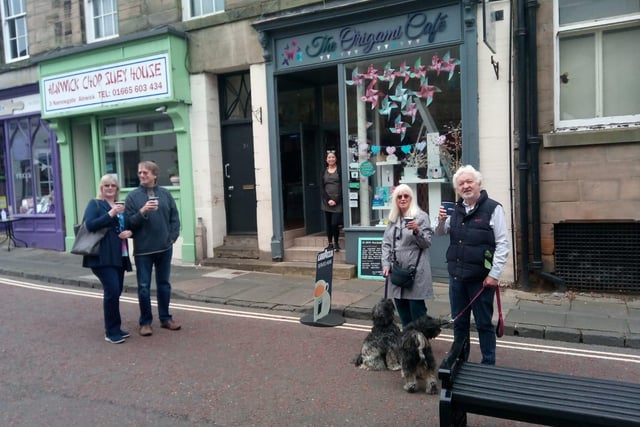 Customers of the Origami Cafe in Alnwick raise their takeaway cups.
