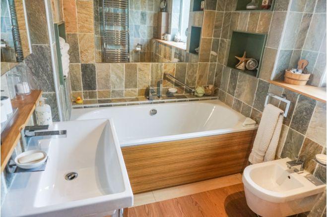 This bathroom is tiled and has a large sink. There's a bath and WC.
