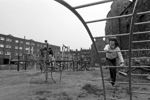 Children playing in an adventure playground in a run-down area of Leith in June 1978. A little girl on the bars.