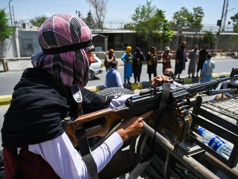 A Taliban fighter mans a machinegun on top of a vehicle as they patrol along a street in Kabul