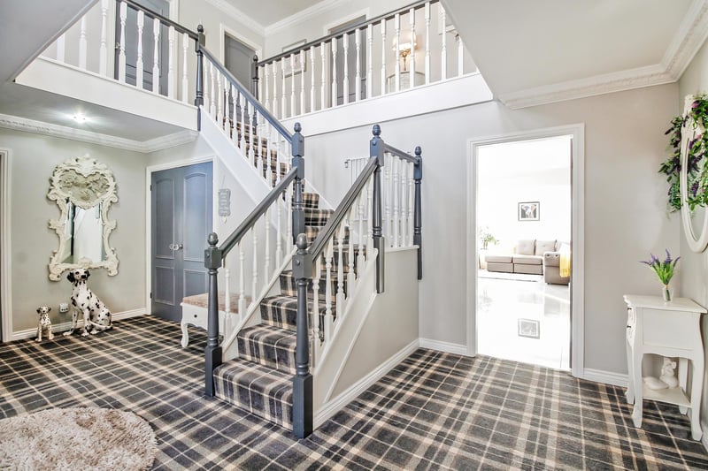 A fantastic-sized entrance hall with stairs leading to the first floor and a storage cupboard with double doors,