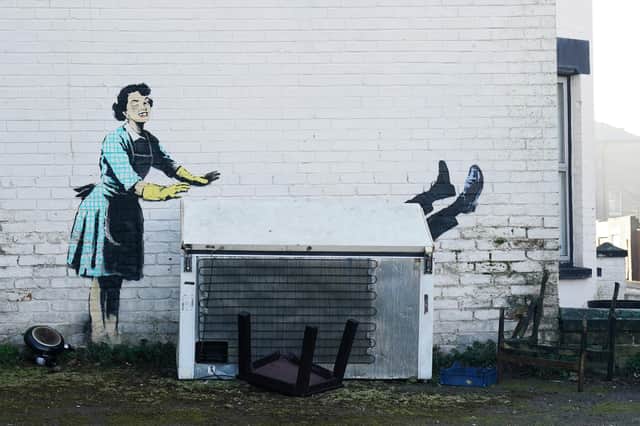 File photo dated 14/2/2023 of the artwork by street artist Banksy, titled 'Valentine's Day Mascara' on the side of a building in Margate, Kent. The artwork depicts a 1950's housewife, wearing a classic blue pinny and yellow washing up gloves, with a swollen eye and a missing tooth seemingly shoving her male partner into a chest freezer. The £6 million work has been lifted by crane into a new exhibition in London. Issue date: Tuesday September 12, 2023. PA Photo. See PA story ARTS Banksy. Photo credit should read: Gareth Fuller/PA Wire 