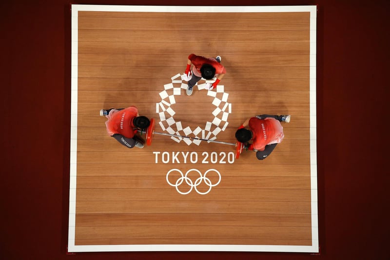 Volunteers change weights during the Weightlifting - Women's 59kg Group A on day four of the Tokyo 2020 Olympic Games at Tokyo International Forum