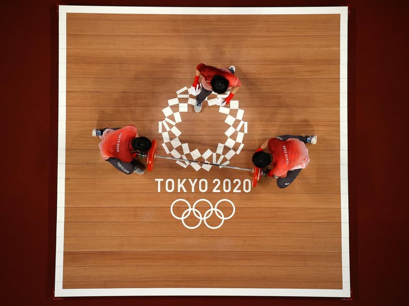 Volunteers change weights during the Weightlifting - Women's 59kg Group A on day four of the Tokyo 2020 Olympic Games at Tokyo International Forum